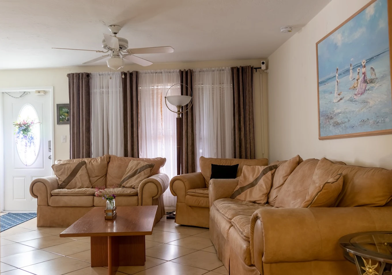 The welcoming living room of the home, with sofas, sunlight, and family photos