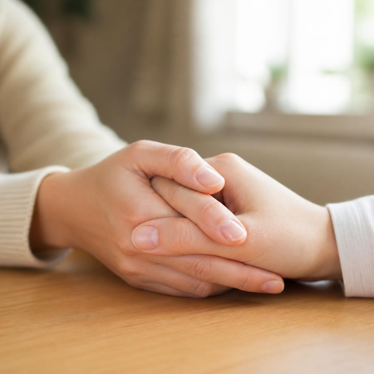 Two hands gently clasped together across a table